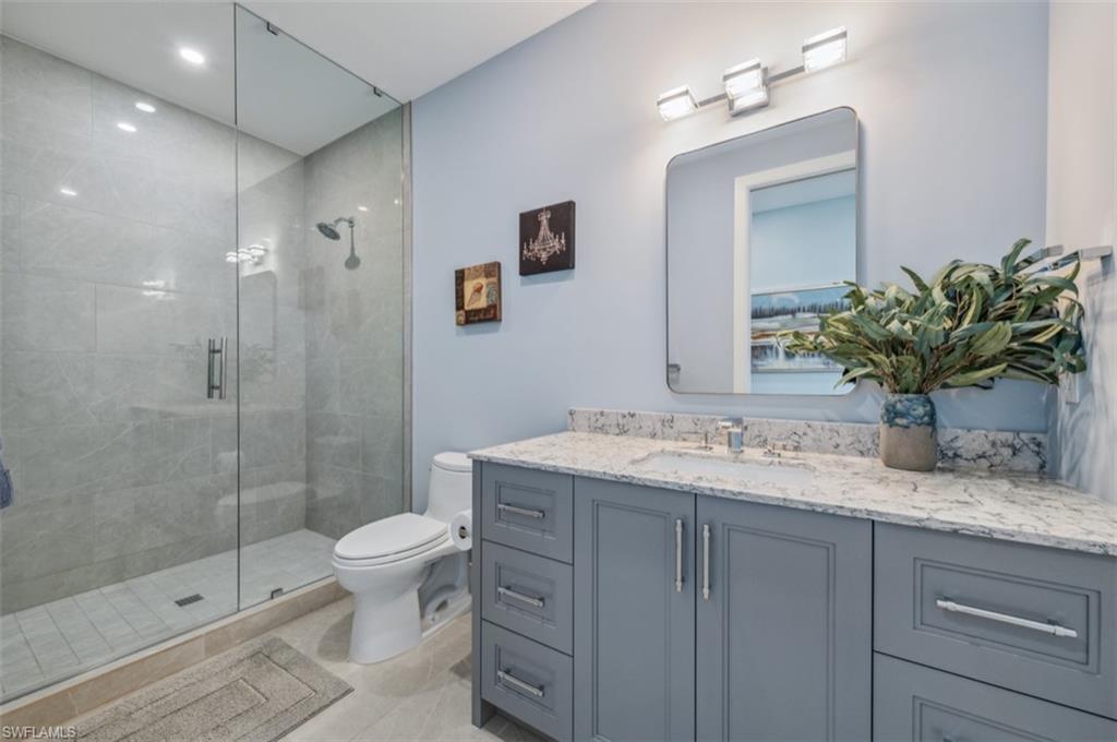 13925 Old Coast Road, Unit PH02 Naples, FL 34110 - Photo 30 of 33 a bathroom with a granite countertop sink a toilet and shower