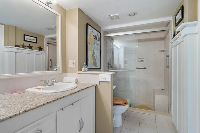 a bathroom with a granite countertop sink a toilet and shower