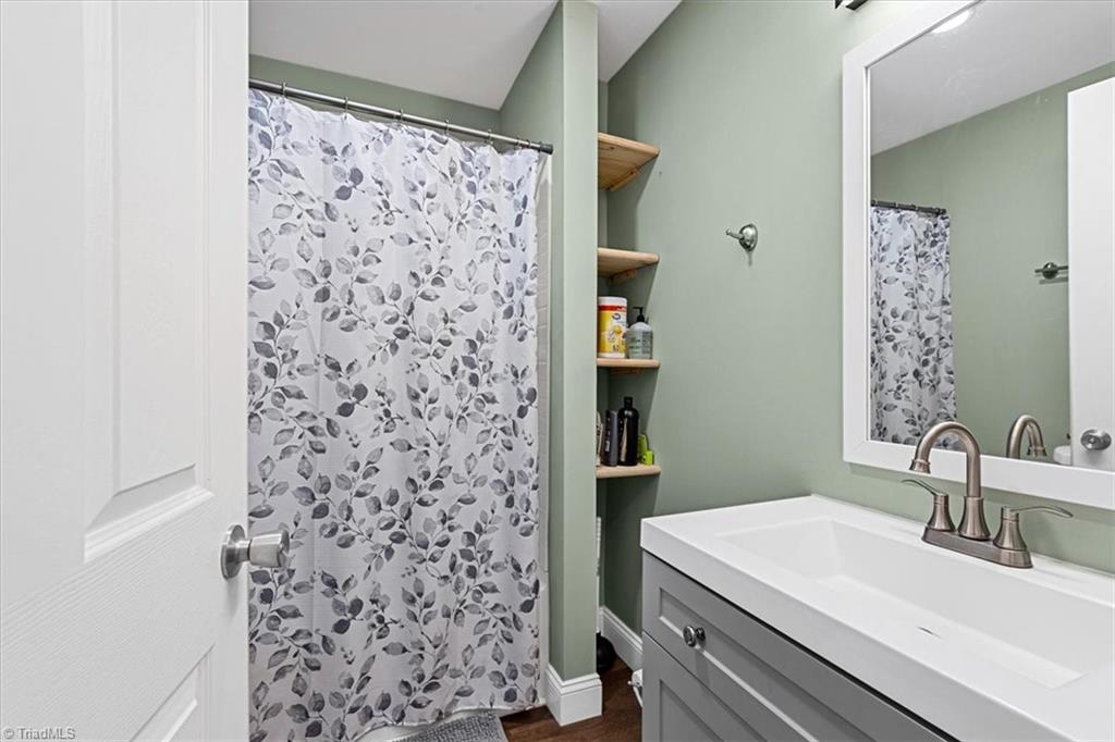 226 Friendly Avenue High Point, NC 27260 - Photo 26 of 38 The main level full bathroom with built in shelves, features a tub and shower combination and a tiled surround, one of three full bathrooms at this High Point property.