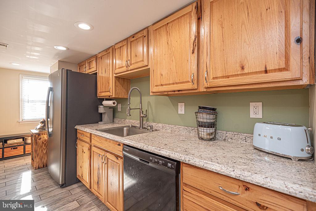 9530 Peerless Road Bishopville, MD 21813 - Photo 11 of 51 a kitchen with stainless steel appliances granite countertop a sink a stove and a wooden cabinets
