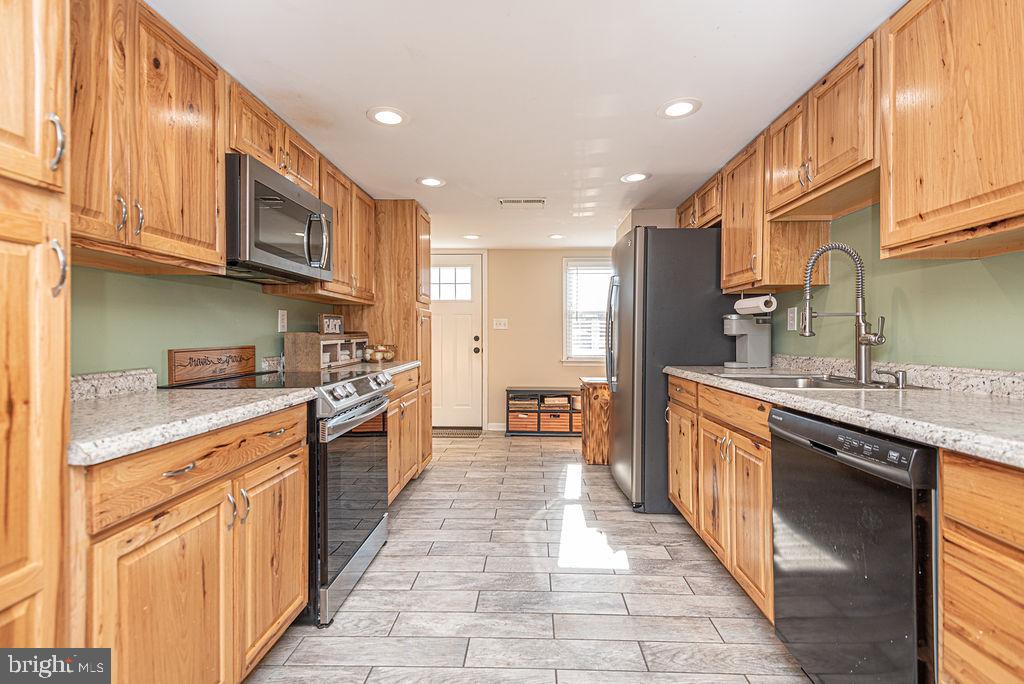 9530 Peerless Road Bishopville, MD 21813 - Photo 10 of 51 a large kitchen with stainless steel appliances granite countertop a large stove top oven a sink dishwasher and cabinets with wooden floor