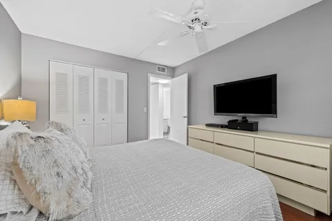 a bedroom with a bed and a flat tv screen on dresser