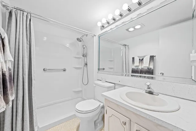 a bathroom with a sink a toilet and shower a mirror