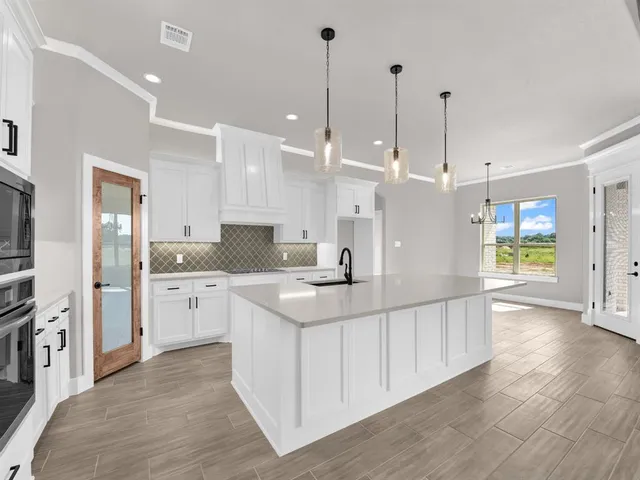 a large white kitchen with a large kitchen island white cabinets and stainless steel appliances