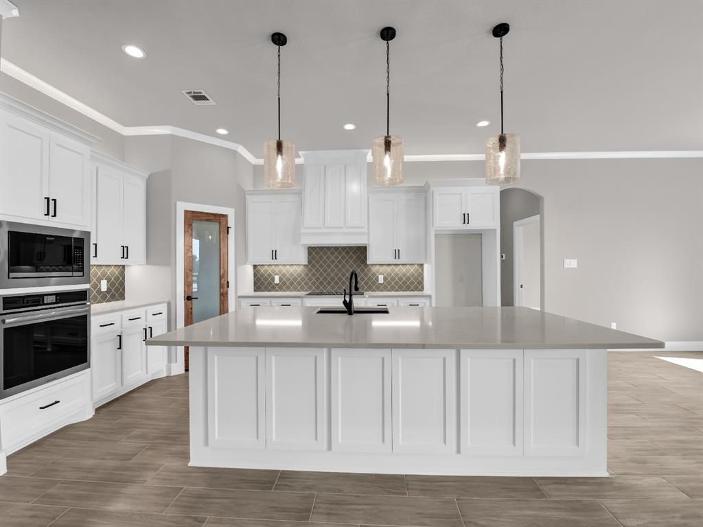 2000 Forest Bridge Drive Azle, TX 76020 - Photo 16 of 34 a large kitchen with kitchen island a stove a sink a center island and wooden floor