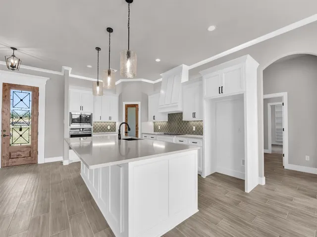 a large kitchen with stainless steel appliances kitchen island granite countertop a refrigerator a oven and a wooden floors