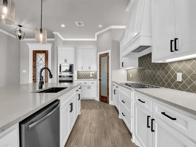 a large kitchen with granite countertop a sink dishwasher a stove and a refrigerator with wooden floor