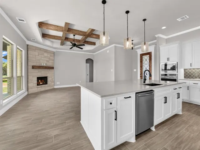 a kitchen with stainless steel appliances granite countertop a sink a stove and a wooden floors