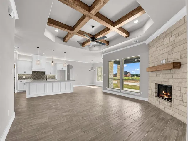a view of an empty room with a fireplace and a ceiling fan