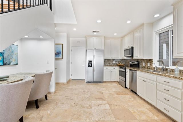 a kitchen with white cabinets stainless steel appliances and window
