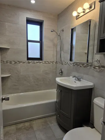 a bathroom with a sink vanity mirror bathtub shower and a toilet