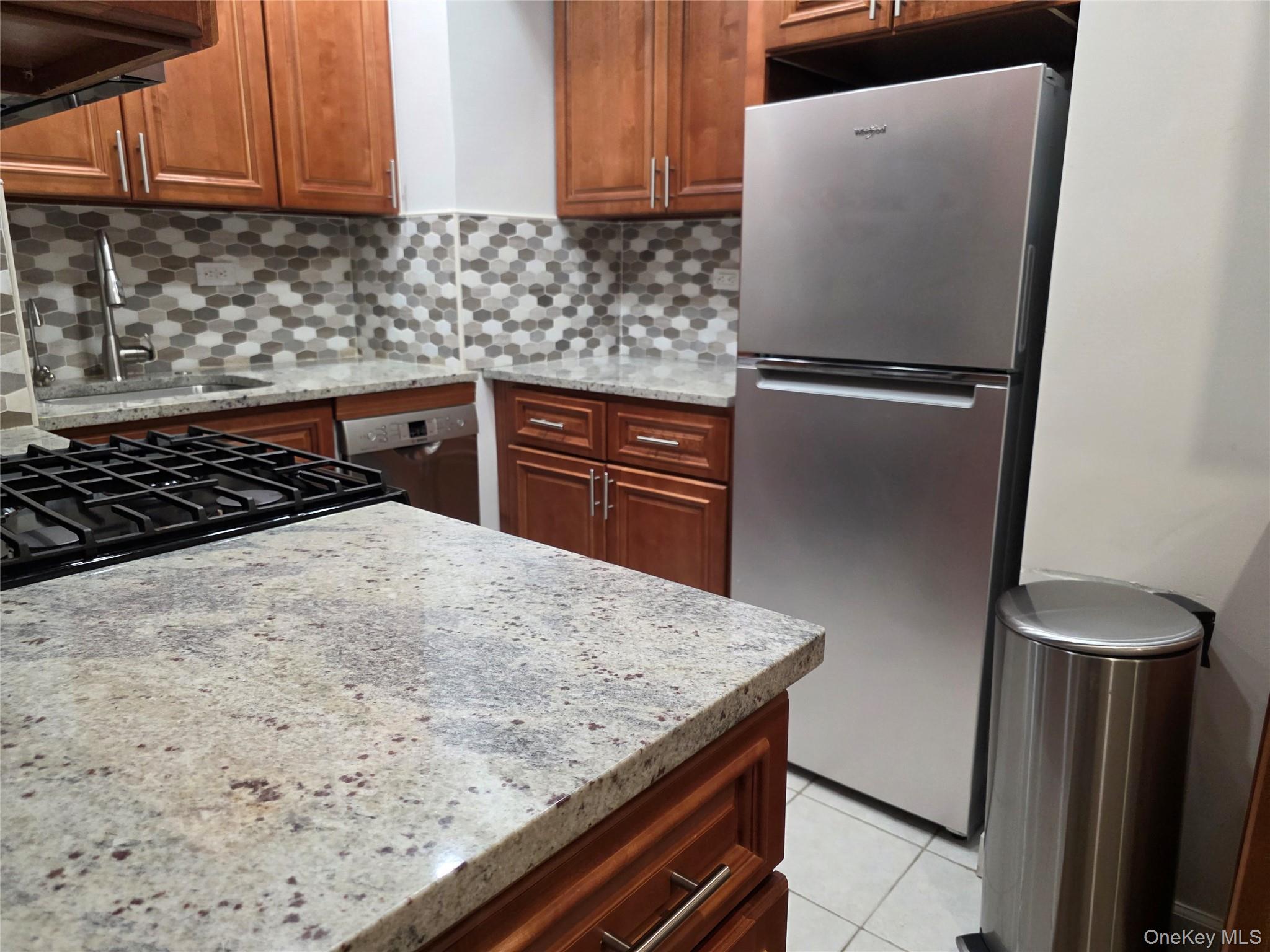 84-01 Main Street, Unit 506 Queens, NY 11435 - Photo 8 of 25 a kitchen with granite countertop a refrigerator and a stove