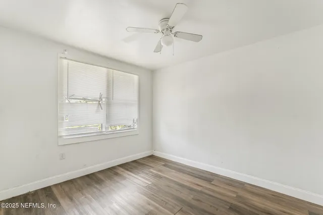an empty room with wooden floor chandelier fan and windows