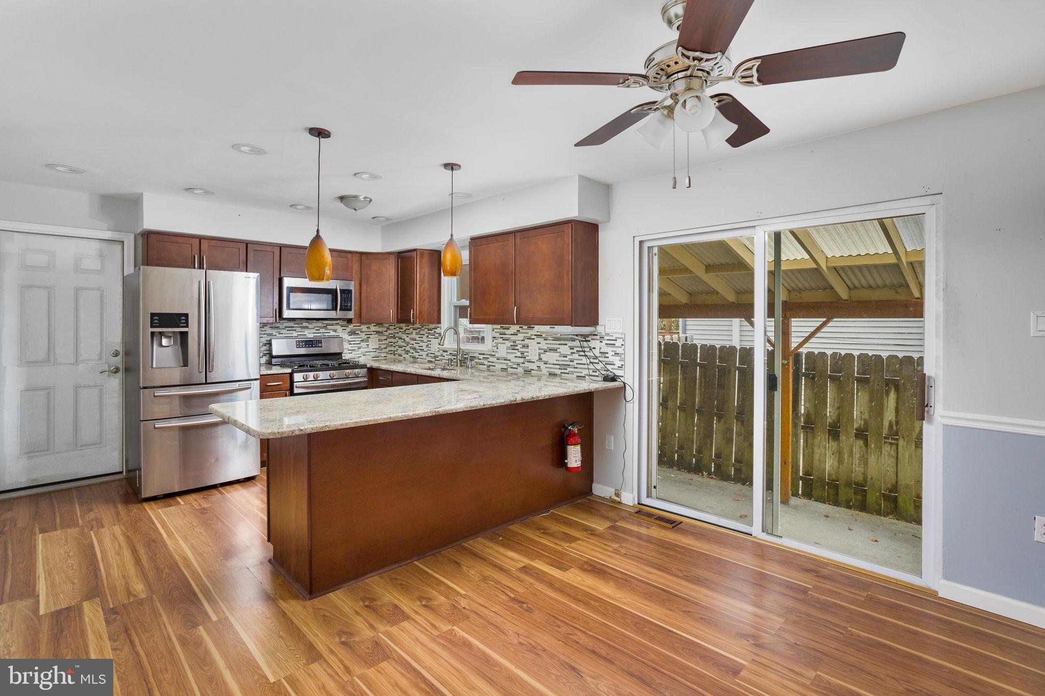 400 Reading Avenue Barrington, NJ 08007 - Photo 9 of 35 a kitchen with stainless steel appliances kitchen island granite countertop a refrigerator a stove and a wooden floors