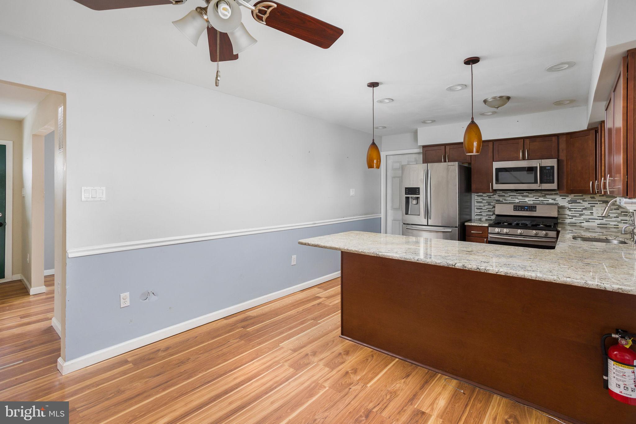 400 Reading Avenue Barrington, NJ 08007 - Photo 10 of 35 a kitchen with stainless steel appliances a microwave a stove and a wooden floor