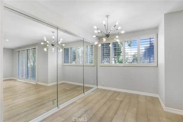 a view of an empty room with chandelier fan and kitchen view