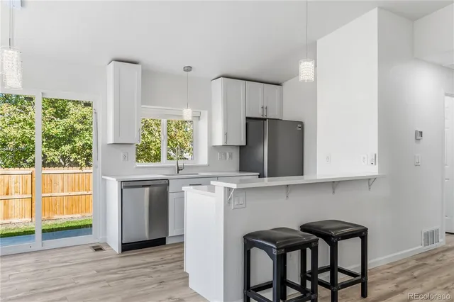 a kitchen with stainless steel appliances a white table chairs in it and wooden floors