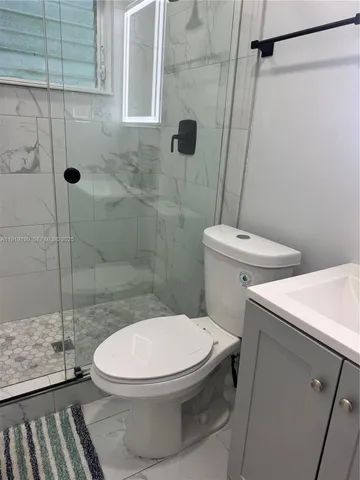 a white toilet sitting next to a shower