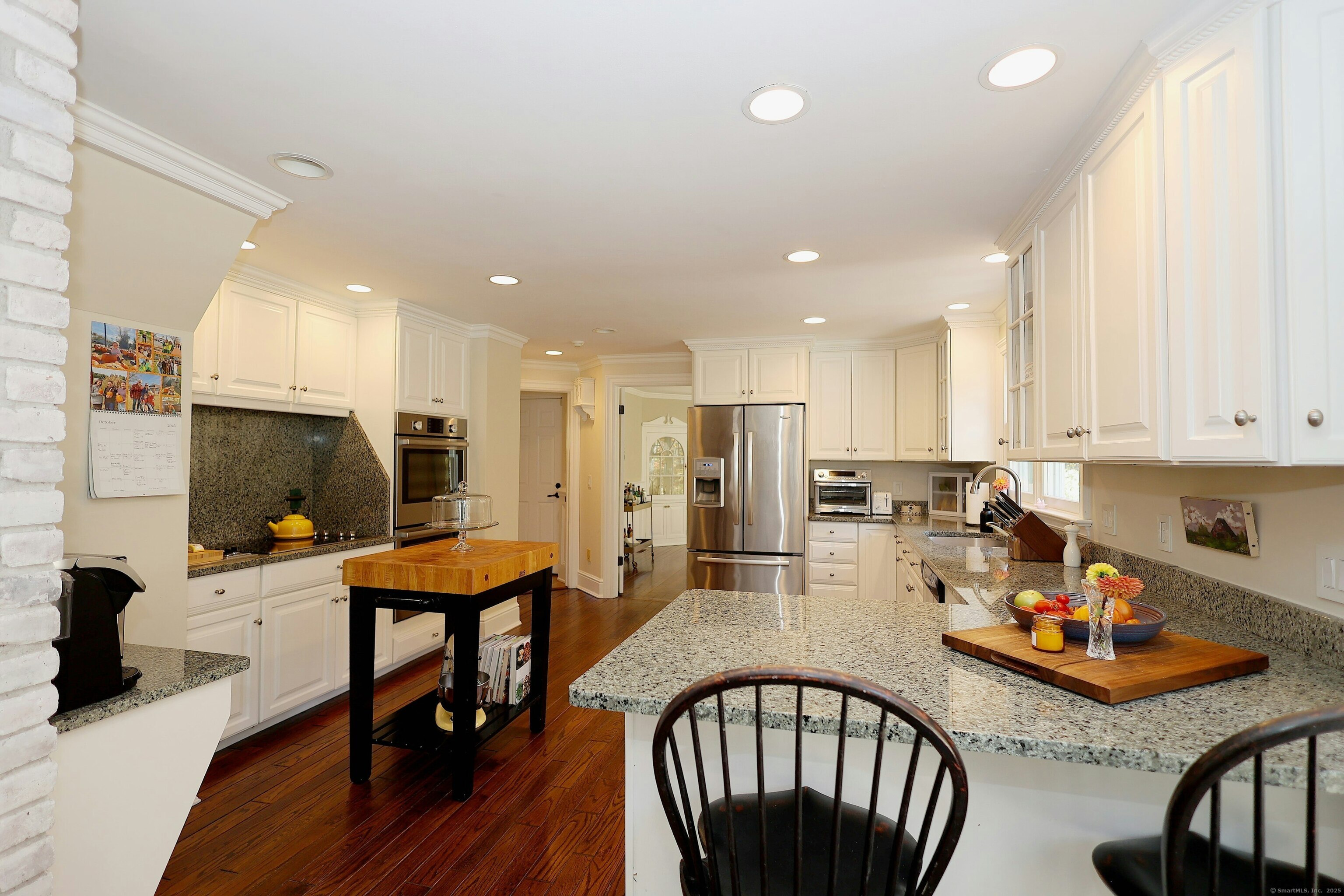 112 Middlebrook Farm Road Wilton, CT 06897 - Photo 18 of 40 a kitchen with stainless steel appliances granite countertop a stove a refrigerator a kitchen island a dining table and chairs with wooden floor