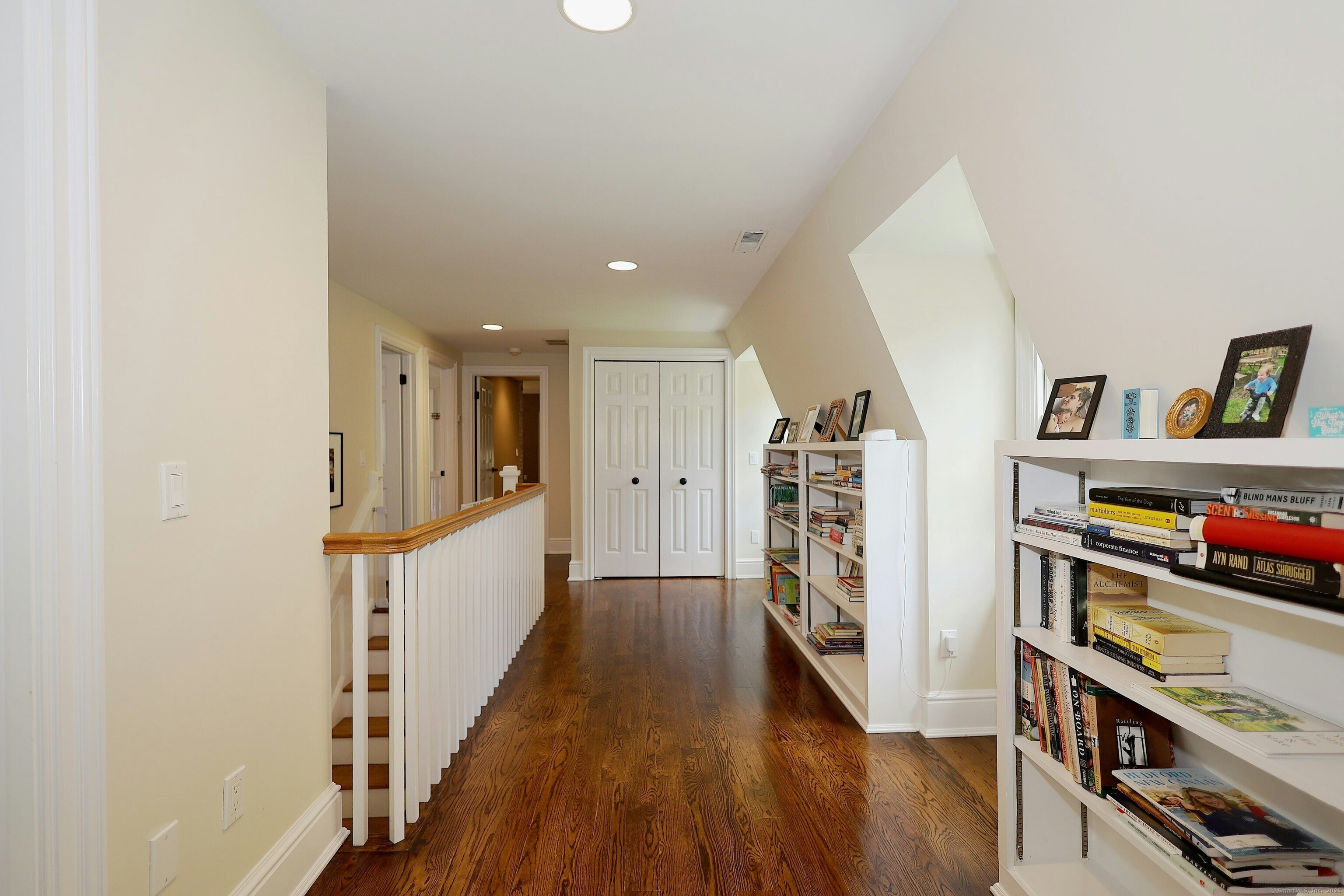 112 Middlebrook Farm Road Wilton, CT 06897 - Photo 29 of 40 a hallway with wooden floor book shelf and living room