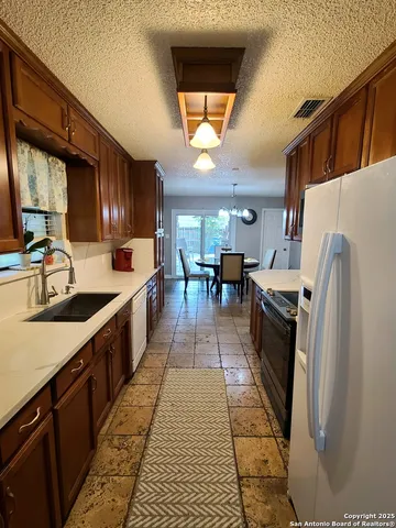 a large kitchen with stainless steel appliances granite countertop a stove a sink dishwasher and a refrigerator with wooden cabinets