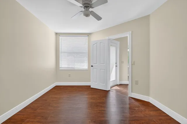 an empty room with wooden floor closet and windows