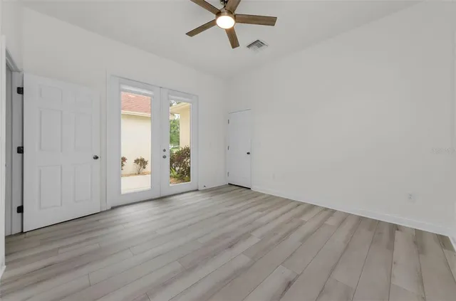 an empty room with wooden floor fan and windows