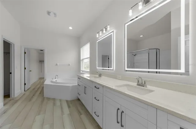 a spacious bathroom with a tub sink and mirror