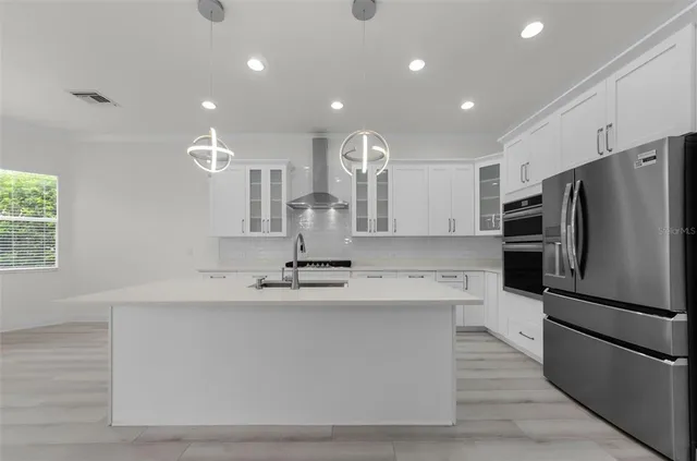 a large kitchen with stainless steel appliances a large counter top a sink and a refrigerator