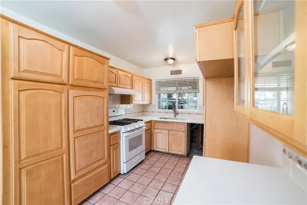 a kitchen with stainless steel appliances granite countertop a refrigerator a sink dishwasher a stove with white cabinets and wooden floor