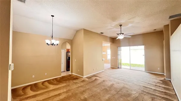 a view of a livingroom with a chandelier fan and windows