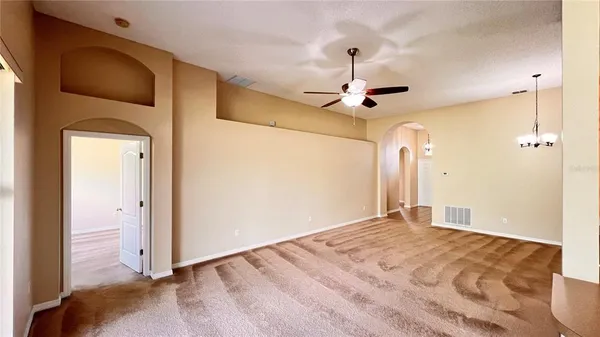 a view of a livingroom with a ceiling fan & windows