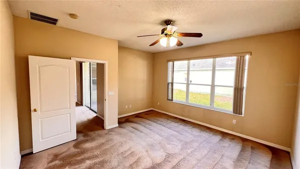 a view of an empty room with window and chandelier fan