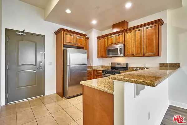 a kitchen with stainless steel appliances granite countertop a refrigerator a sink and a stove
