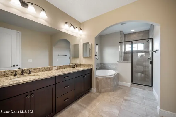 a spacious bathroom with a double vanity sink toilet mirror and bathtub
