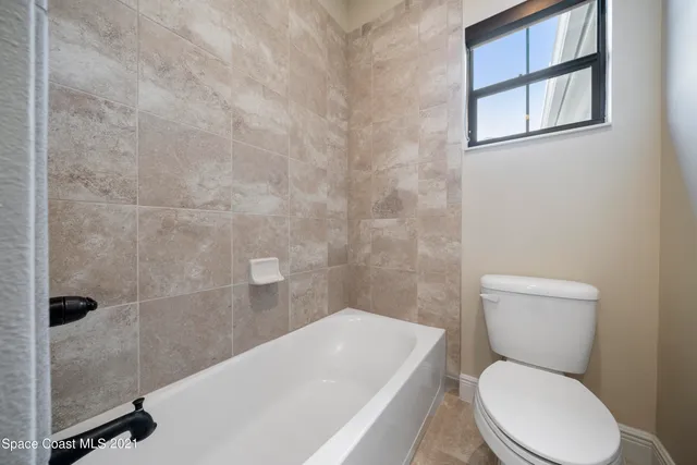 a white toilet sitting next to a bath tub and a wooden door