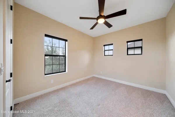 an empty room with windows and fan