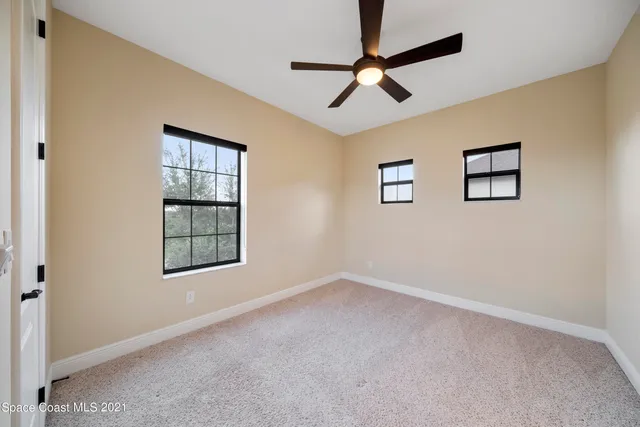 an empty room with windows and fan