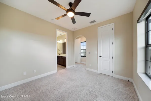 an empty room with chandelier fan and windows