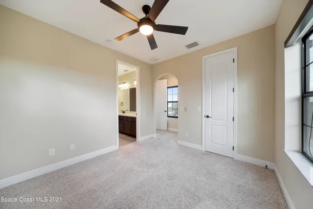an empty room with chandelier fan and windows