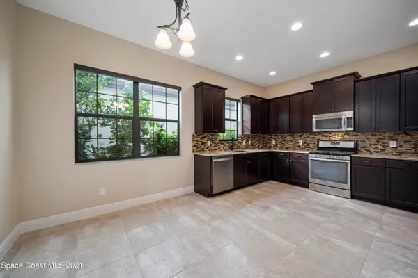 a kitchen with kitchen island granite countertop stainless steel appliances cabinets a sink and a window
