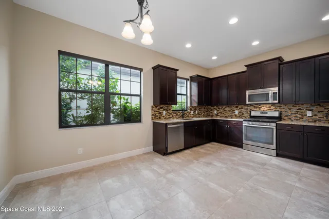 a kitchen with kitchen island granite countertop stainless steel appliances cabinets a sink and a window