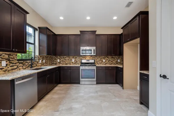 a large kitchen with a sink and refrigerator