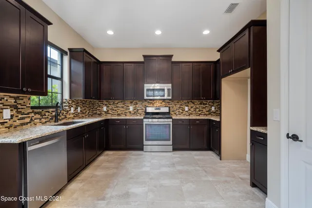 a large kitchen with a sink and refrigerator