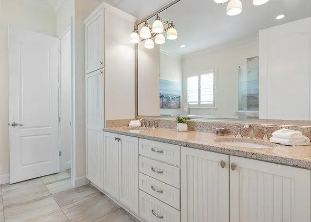 a bathroom with double vanity sinks a vanity a lamp and a mirror