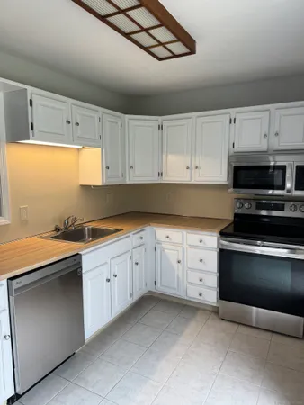 a kitchen with granite countertop white cabinets and stainless steel appliances