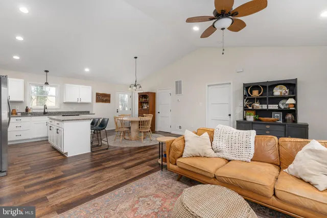 a kitchen with stainless steel appliances granite countertop a dining table chairs refrigerator and sink