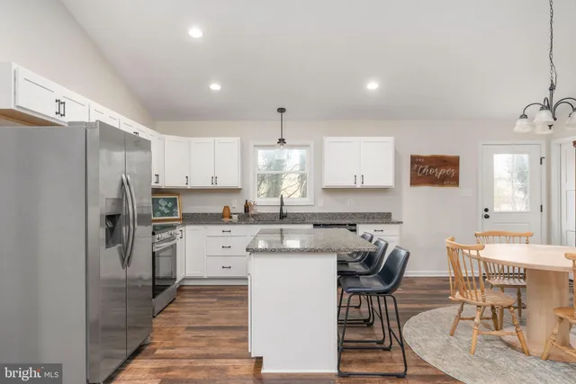 a kitchen with stainless steel appliances granite countertop a stove a sink a microwave a refrigerator and white cabinets