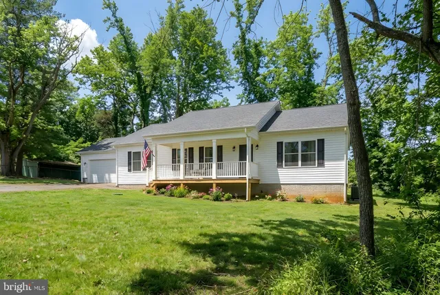 a view of a house with a yard deck and a large tree