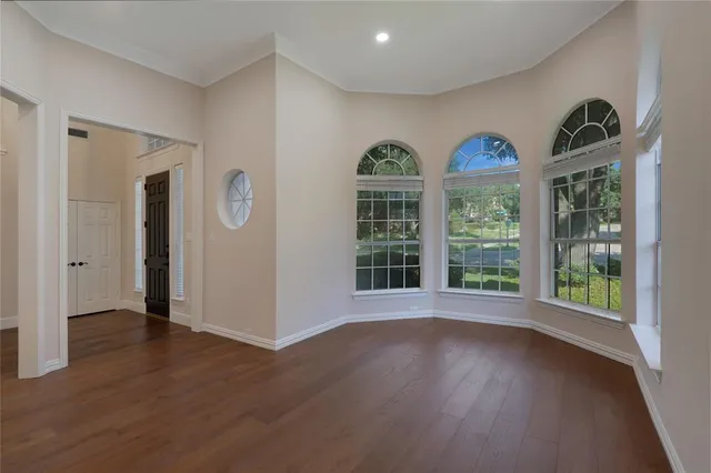 an empty room with wooden floor chandelier and window